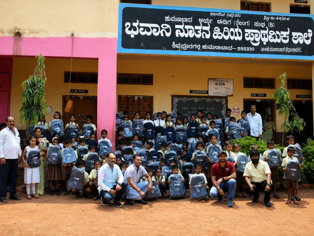 Schoolchildren holding CDS-branded school bags outside their government primary school.